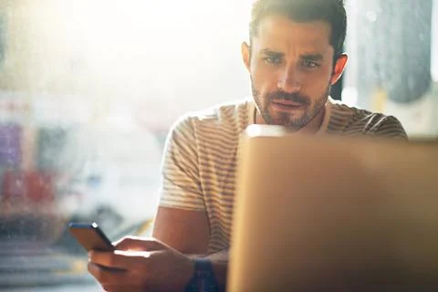 Getting some admin done. Shot of a young man using his laptop in a coffee sho Stock Photos