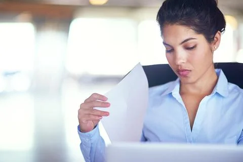 Getting some admin out of the way. a young businesswoman going over documents 写真素材
