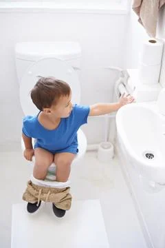 Getting some toilet paper. a young boy reaching for toilet paper in a bathroom. Stock Photos