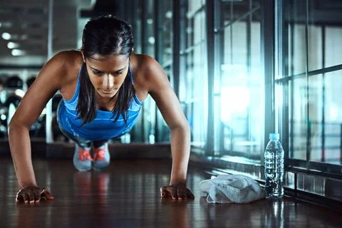 Getting stronger with every rep. an attractive young woman doing pushups as part Stock Photos