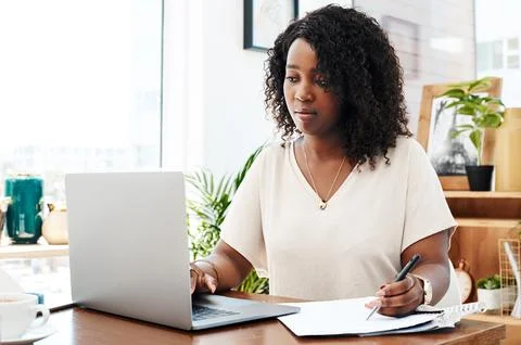 Getting stuck right in to a new task. a young businesswoman writing notes while Stock Photos