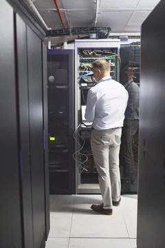 Getting systems sorted and running again. Rearview shot of a mature man using a 写真素材