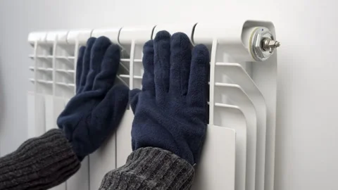 Getting warm up his hand with glove over an electric radiator Vidéo 286232220