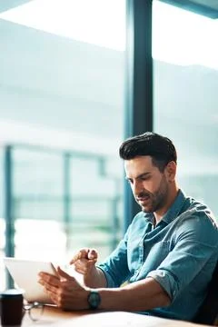 Getting work done in digital format. a young businessman using a digital tablet Stock Photos