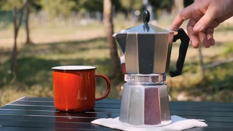 Geyser coffee maker is on a table with a red cup. A woman takes a coffee pot Stock Footage 115943171