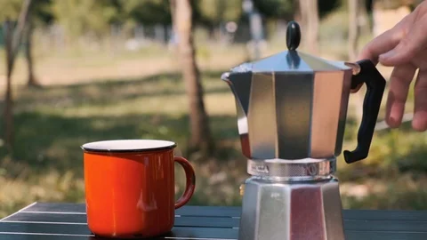 Geyser coffee maker is on a table with a red cup. A woman takes a coffee pot Stock Footage 115943184