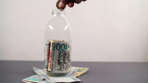 Ghanaian cedi notes and coins in savings jar for personal finance Stock Footage 346165297
