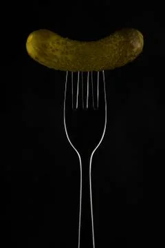 Gherkin on a fork on a dark background Stock Photos