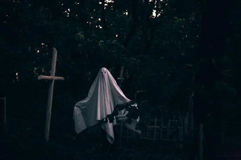 Ghost in the cemetery between graves during Halloween Foto stock