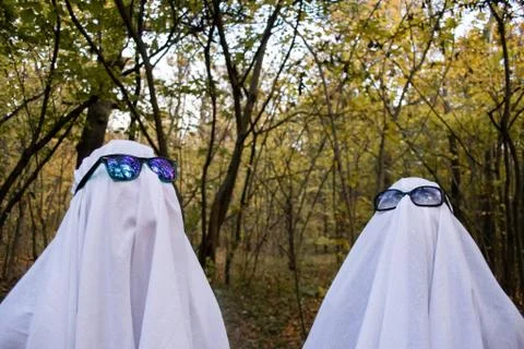 Ghost challenge in the forest. Two teenagers with white bed sheets, sun glasses Stock Photos