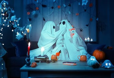 Ghost couple eats popcorn during a spooky Halloween party at home, celebrat.. 写真素材
