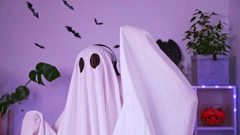 A ghost is dancing at a Halloween party. The ghost listens to music with Stock Footage 219733279
