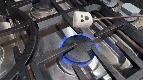 Ghost face marshmallow roasting over a gas stove catches on fire for Halloween Stock Footage 140673336
