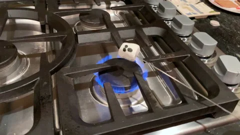 Ghost face marshmallow roasting over a gas stove catches on fire for Halloween Stock Footage 140673789