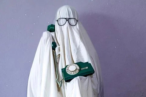 A ghost figure made from a white bedsheet and wearing glasses holds a retro.. Stock Photos