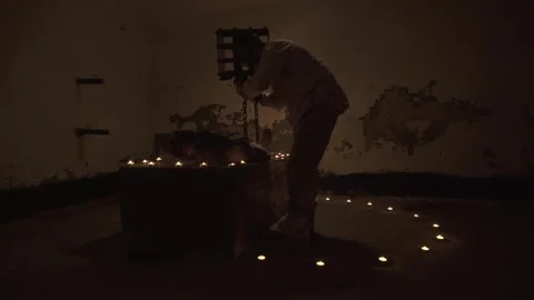 Ghost performing sacrifice and eating flesh of man lying on altar in basement. Stock Footage 245577015