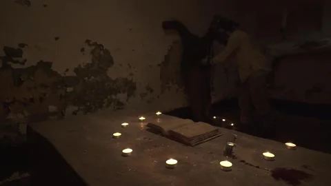 Ghost performing sacrifice and eating flesh of crucified man in gloomy basement. Stock Footage 245577182