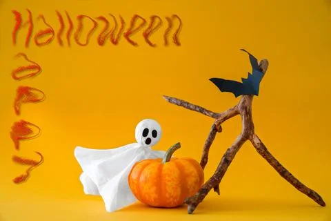 Ghost, pumpkin, bats on orange background, inscription Happy Halloween. Stock Photos