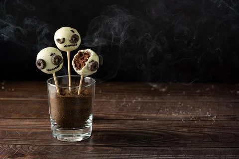 Ghost shaped cake pops on a dark wooden table with smoke on a black background Stock Photos