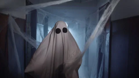 Ghost in white sheet dancing in old corridor with cobwebs in blue smoke on Stock Footage 313552492