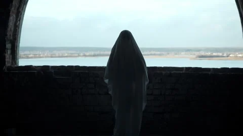 Ghost in white sheet stands before old window, vast river and autumn landscape Stock Footage 320247864