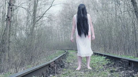 ghost of woman stands in forest on railway track