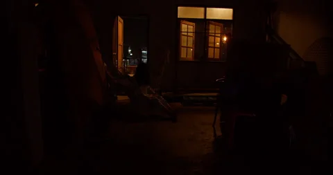 Ghostly figure sits motionless in a hammock within a dark and cluttered room Video stock 345666117