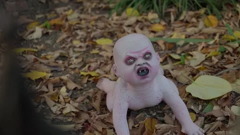 A ghoulish doll decoration lying in fallen leaves at Halloween Stock Footage 345299637