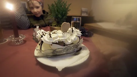 Giant banana split on table in front of boy at restaurant with fog Stock Footage 121754255