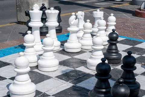 Giant chess board with large white and black pieces in an outdoor public park. Stock Photos
