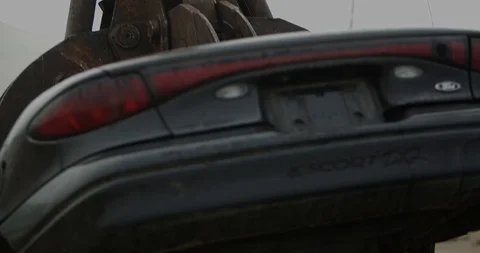 Giant claw machine crushing and lifting car at junkyard - 4K with sound Video stock 115358162