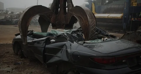 Giant claw machine crushing and lifting car at junkyard - 4K with sound Stock Footage 115360418