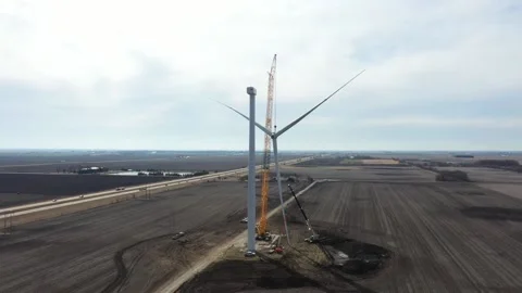 Giant crane with lifted windmill blade close to the rotor of the windmill Stock Footage 151072359