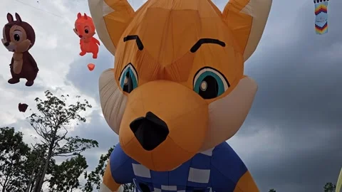 A giant inflatable fox kit with expressive blue eyes flying in the sky. Stock Footage 304401822