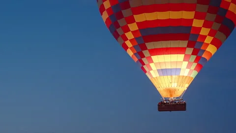 A giant multicolored hot air balloon with people in the basket, close-up during Stock Footage 252175825