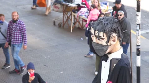 A giant puppet with face mask walking in the street during the COVID Stock Footage 133578214
