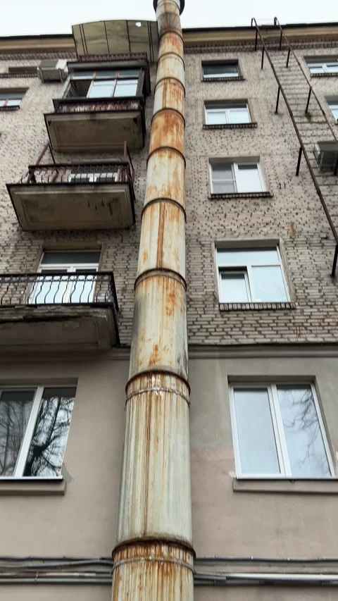 A giant rusty pipe on the facade of an old brick house with windows Stock Footage 269777020