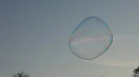 Giant Soap Bubble Floating and Blown by Breeze against Blue Sky Stock Footage 22256600