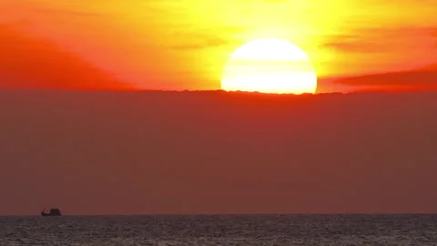 Giant sun setting behind clouds over calm ocean horizon 스톡 동영상 340919855