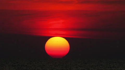 Giant sun setting over dark ocean horizon under crimson red sky Stock Footage 336896420