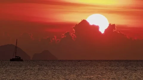 Giant Sunset Sun Behind Red Clouds with Catamaran and Island Silhouettes Видео 333547396