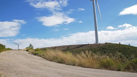 Giant Windmill at the end of a Dirty Road. Grasslands swaying by the Wind. Green Stock Footage 146088902