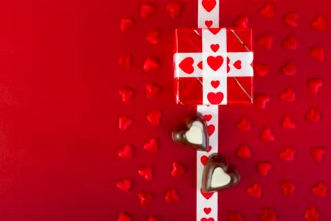 Gift and chocolate and red hearts on red Stock Photos