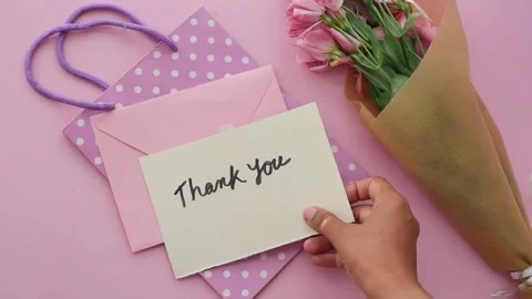Gift bag with flowers and an envelope on a pink surface Stock Footage 341998534