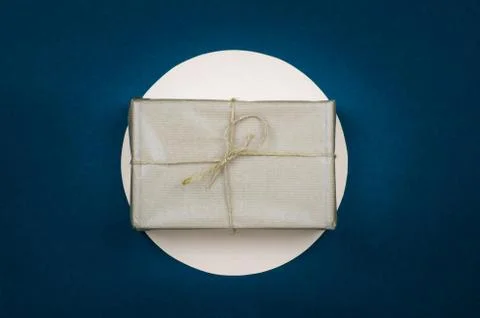 Gift in a beige wrapper on a blue background. A holiday gift. Stock Photos