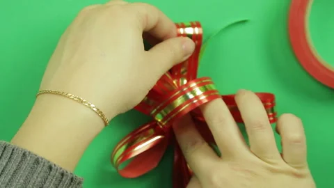 Gift bow of shiny red ribbon on a green background Stock Footage 99512085