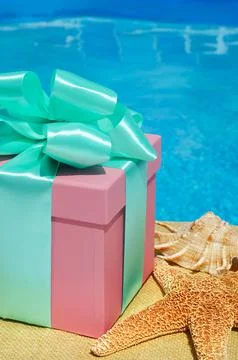 Gift box and a large starfish on the background of the pool. Stock Photos