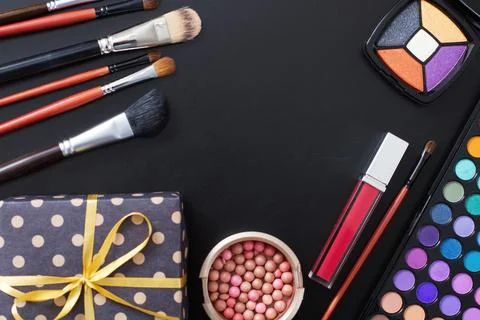 Gift box and makeup tools and accessories isolated on black background. Top.. Stock Photos