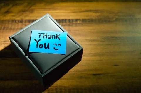 A gift box and a note that said "Thank you" written on it with a ray of lig.. Foto stock