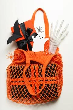 Gift box and paper ghost and bat in shopping bag on white background, top vie Stock Photos